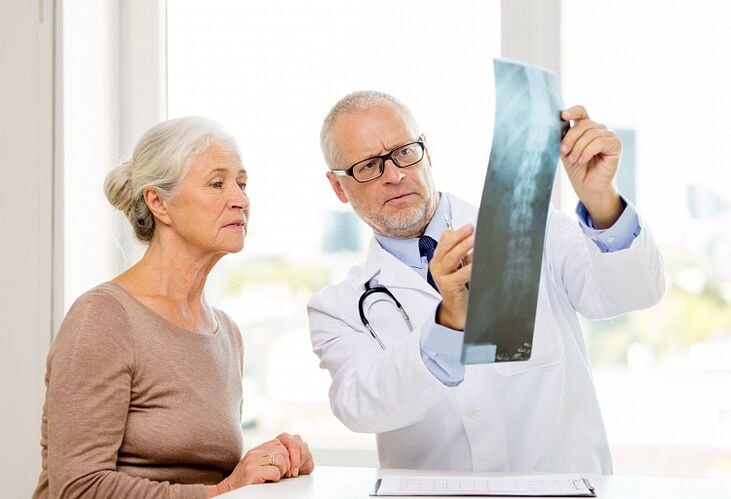 De arts bepaalt cervicale osteochondrose bij een patiënt met behulp van radiografie